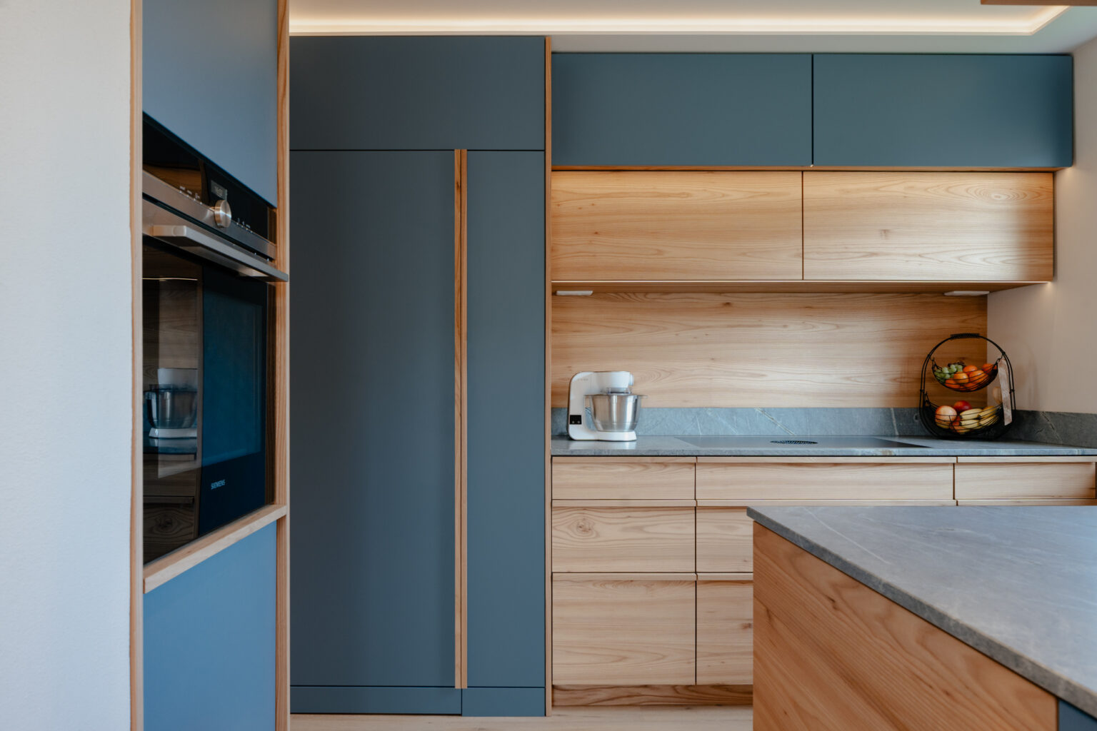 Küche in Kombination mit Holz Rüster furniert und blau mit Steinarbeitsplatte Atlantik
