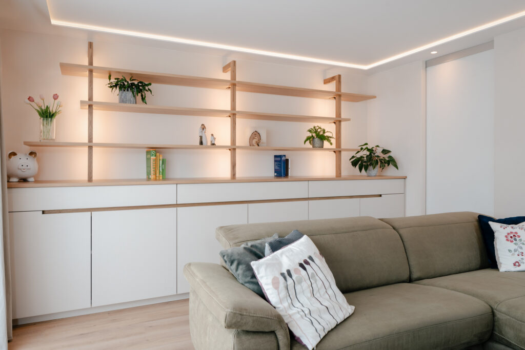Wohnzimmmer Wand mit viel Stauraum und Regal aus Holz mit indirekter Beleuchtung vom Tischler
